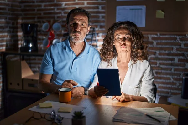 Middle Age Hispanic Couple Using Touchpad Sitting Table Night Puffing — Stockfoto