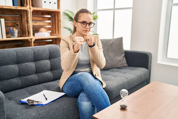 Young woman working at consultation office ready to fight with fist defense gesture, angry and upset face, afraid of problem