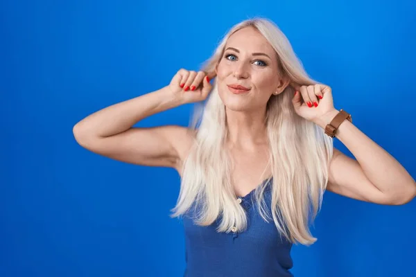 Caucasian Woman Standing Blue Background Smiling Pulling Ears Fingers Funny — Foto de Stock