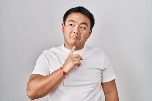 Young Chinese Man Standing White Background Thinking Concentrated Doubt Finger — Stock Photo, Image