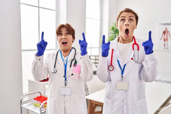 Dos Mujeres Con Uniforme Médico Estetoscopio Asombradas Sorprendidas Mirando Hacia — Foto de Stock