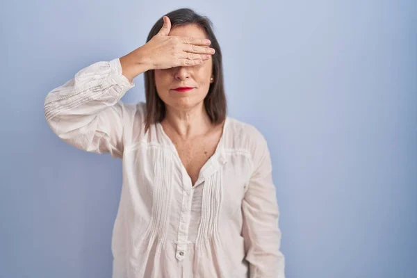 Middle Age Hispanic Woman Standing Blue Background Covering Eyes Hand — Stockfoto