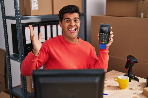 Hispanic Man Working Small Business Ecommerce Holding Dataphone Celebrating Victory — Stock Fotó