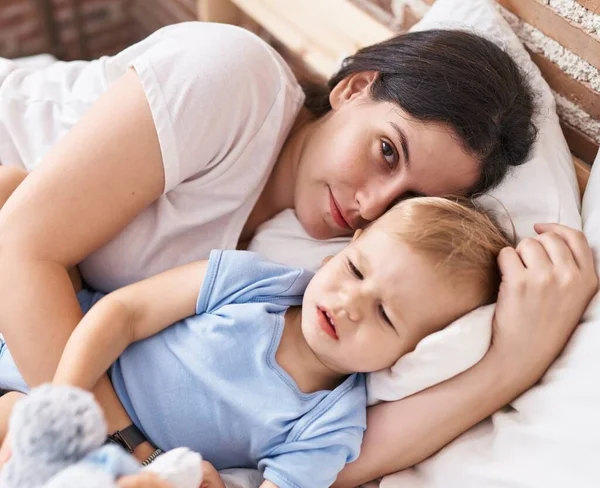 Mother and son lying on bed hugging doll at bedroom