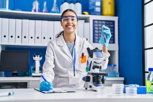 若いアフリカ系アメリカ人女性の科学者は 実験室での血液検査管書き込みレポートを分析 — ストック写真