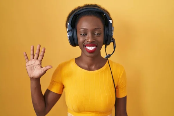 African Woman Curly Hair Standing Yellow Background Wearing Headphones Showing — Stock Photo, Image