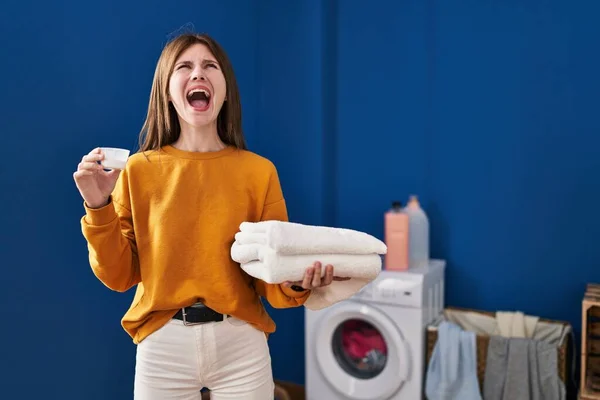 Young Brunette Woman Holding Detergent Clean Laundry Angry Mad Screaming — Stockfoto