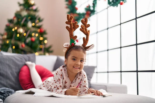 Adorable Hispanic Girl Smiling Confident Lying Sofa Christmas Tree Home — ストック写真