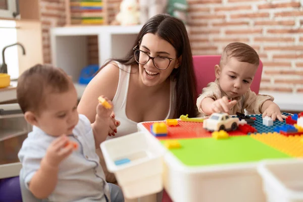 stock image Teacher and preschool students playing with construction blocks sitting on table at kindergarten
