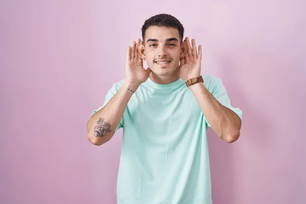 Красивый Латиноамериканец Стоящий Розовом Фоне Пытающийся Услышать Обе Руки Жесте — стоковое фото
