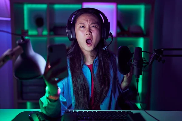 stock image Young asian woman playing video games with smartphone angry and mad screaming frustrated and furious, shouting with anger. rage and aggressive concept. 