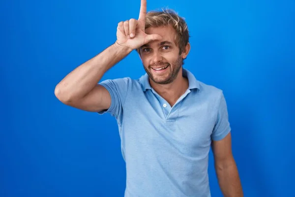 Caucasian Man Standing Blue Background Making Fun People Fingers Forehead — Foto Stock
