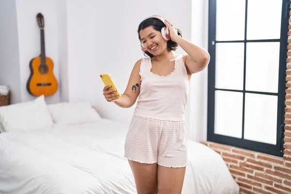 Young woman listening to music and dancing at bedroom