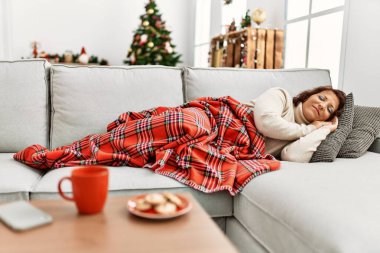Orta yaşlı İspanyol kadın evdeki Noel ağacının yanında kanepede uyuyor..