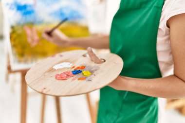 Resim stüdyosunda resim çizen orta yaşlı bir kadın.