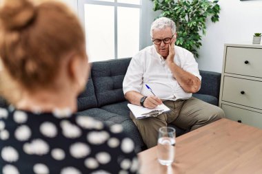 Senior psychologist man at consultation office touching mouth with hand with painful expression because of toothache or dental illness on teeth. dentist concept. 