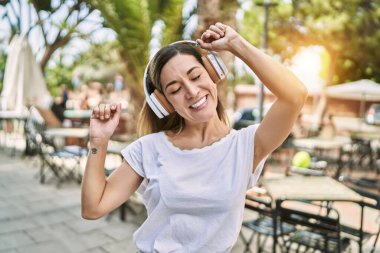 Genç İspanyol kadın sokakta müzik dinlerken kendinden emin gülümsüyor.