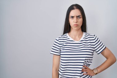 Young brunette woman wearing striped t shirt skeptic and nervous, frowning upset because of problem. negative person. 