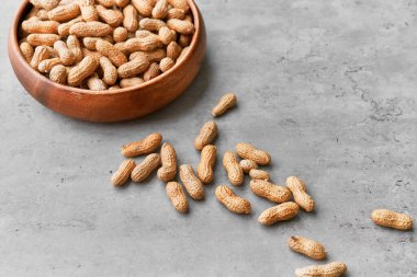 Beton bir yüzeyde kasede bir avuç fıstık.