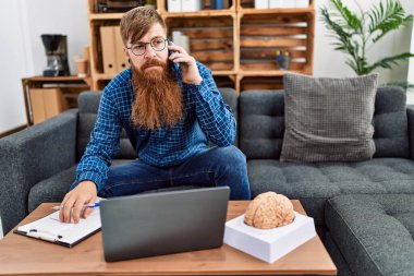 Genç kızıl erkek psikolojisi klinikteki akıllı adamla telekonksiyon konuşması yapıyor.