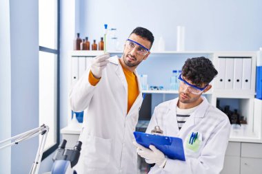 Laboratuvarda çalışan iki bilim adamı test tüpleri tutuyor.