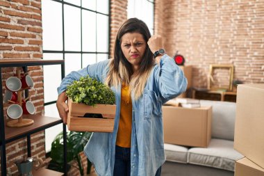 Young hispanic woman moving to a new home holding plants annoyed and frustrated shouting with anger, yelling crazy with anger and hand raised 
