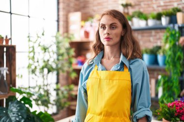Young beautiful hispanic woman florist standing with serious expression at florist