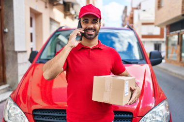 Genç İspanyol kurye caddedeki akıllı telefon paketinden konuşuyor.