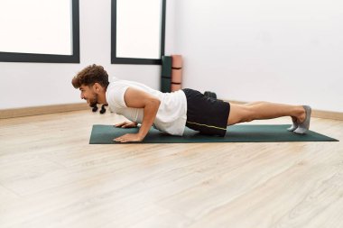 Young arab man smiling confident training abs exercise at sport center