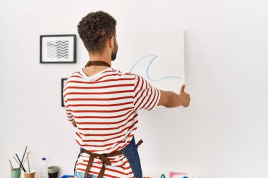 Arkaya bakan genç Arap ressam resim stüdyosunun duvarına resim çiziyor..