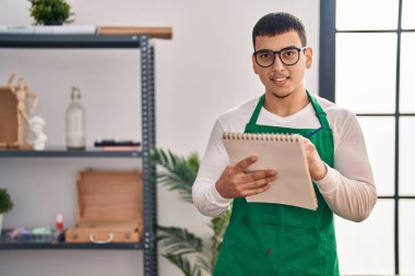 Young man artist smiling confident drawing on notebook at art studio