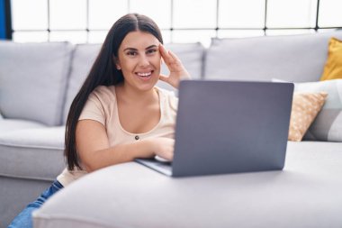 Evde dizüstü bilgisayar kullanan genç, güzel İspanyol kadın.