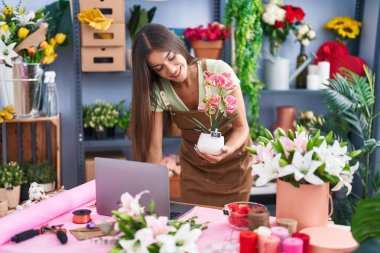 Çiçekçide dizüstü bilgisayar kullanan güzel İspanyol bir çiçekçi.