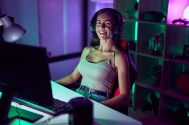 Young beautiful hispanic woman streamer playing video game using computer at gaming room
