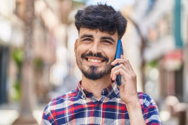 Genç İspanyol adam gülümsüyor. Kendine güveniyor. Sokakta akıllı telefondan konuşuyor.