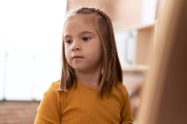 Adorable hispanic girl standing with relaxed expression at kindergarten