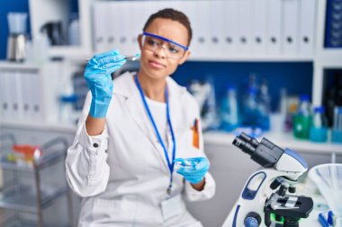 African american woman scientist holding pill at laboratory