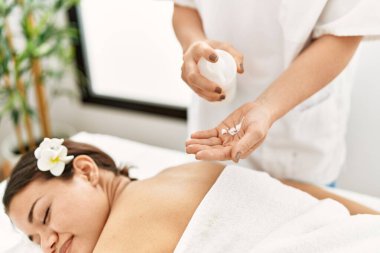Young latin woman relaxed having back massage with moisturizer at beauty center