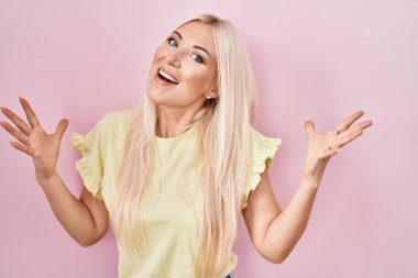 Caucasian woman standing over pink background celebrating crazy and amazed for success with arms raised and open eyes screaming excited. winner concept 
