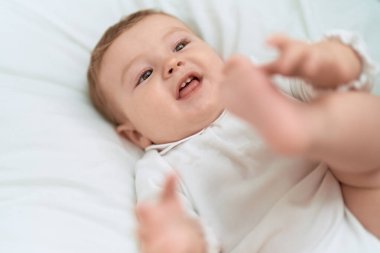 Sevimli çocuk yatakta kendinden emin bir şekilde gülümsüyor.