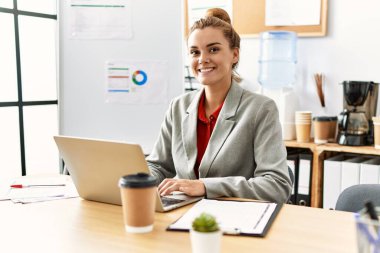 Ofiste çalışan genç bir iş kadını dizüstü bilgisayar kullanıyor.