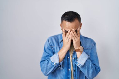 İzole edilmiş arka planda duran genç İspanyol bir adam. Ağlarken suratını ellerle kapatan üzgün bir ifade. depresyon kavramı. 