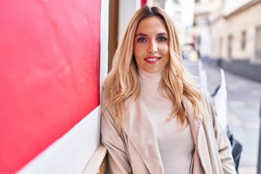 Sokakta kendine güvenen genç sarışın kadın gülümsüyor