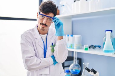 Young caucasian man scientist standing with relaxed expression at laboratory