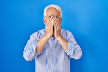 Hispanic senior man wearing glasses rubbing eyes for fatigue and headache, sleepy and tired expression. vision problem 