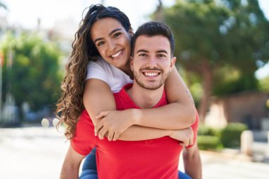 Young hispanic couple smiling confident hugging each other holding on back at street