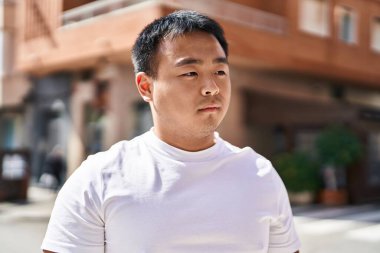 Young chinese man standing with relaxed expression at street