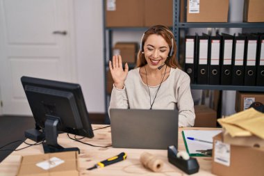 Hispanic woman working at small business ecommerce wearing headset looking positive and happy standing and smiling with a confident smile showing teeth 
