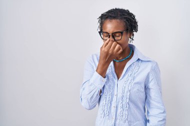 African woman with dreadlocks standing over white background wearing glasses tired rubbing nose and eyes feeling fatigue and headache. stress and frustration concept. 