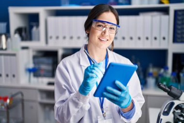 Young woman scientist using touchpad at laboratory
